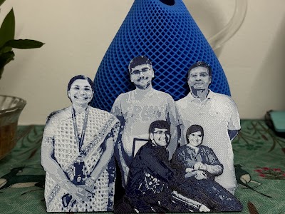 Cool-grey 3D-printed family relief of five people, standing on a home table.