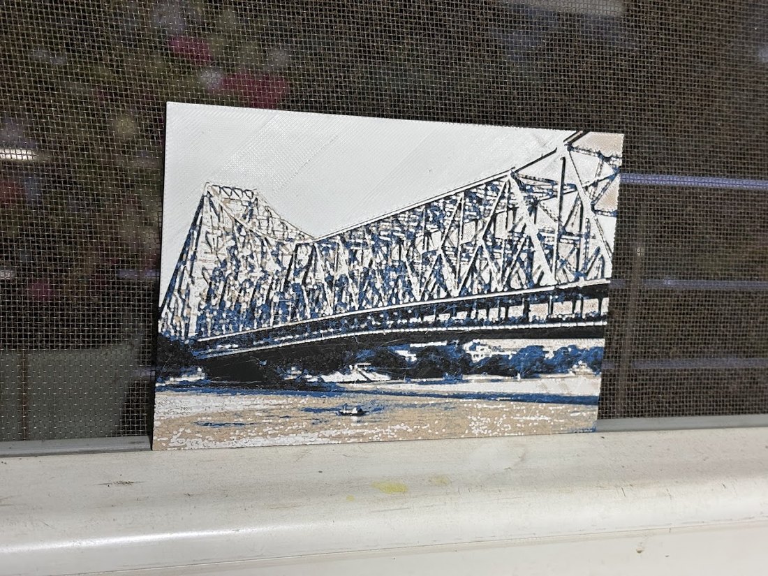 3D-printed plaque of Howrah Bridge standing on a windowsill.